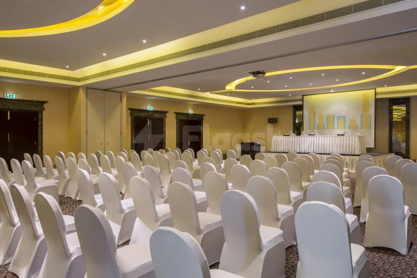 Meeting room at Metropolitan Al Mafraq Hotel in Abu Dhabi with white chair covers and bar chart projection