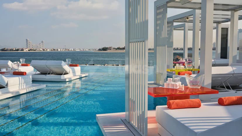 Rooftop terrace at BCH CLB in Dubai featuring an infinity pool and white lounge chairs with orange towels