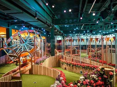 Indoor mini golf course at Swingers The Crazy Golf Club Dubai with decorative windmill and artificial turf