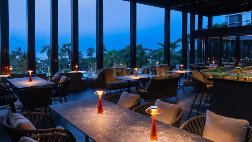 TakaHisa Restaurant Dubai features a modern indoor-outdoor dining space with floor-to-ceiling glass walls overlooking palm trees