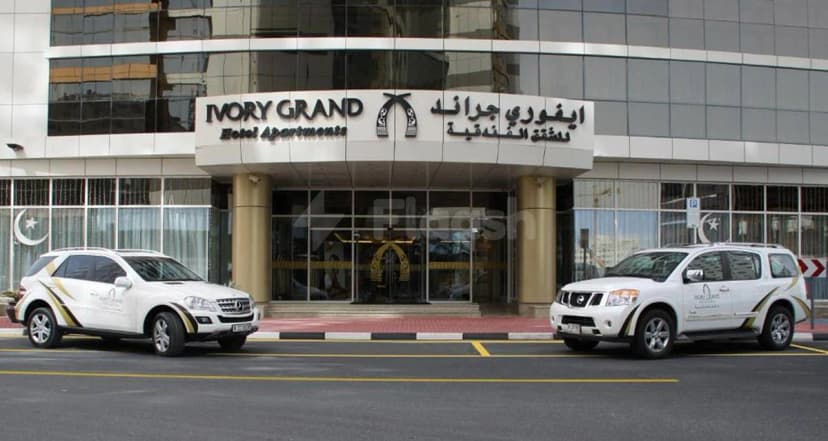 Hotel facade at Ivory Grand Hotel Apartments in Dubai with gold-striped white SUVs parked outside