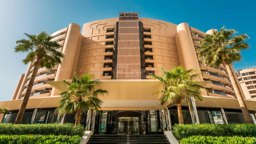 Hotel facade at Le Royal Meridien Beach Resort & Spa in Dubai with tall palm trees