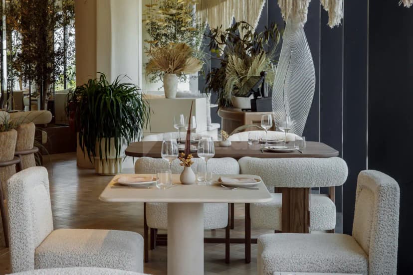 OSH Del Mar Restaurant Dubai Marina dining area with textured white chairs, wooden tables, potted plants
