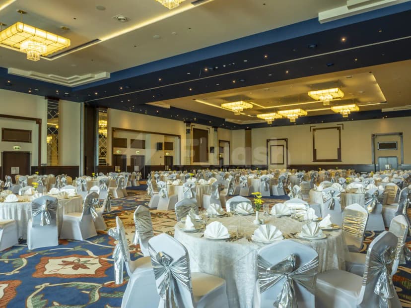 Ballroom at Retaj Salwa Resort & Spa in Doha with round tables, silver chair bows, and blue ceiling trim