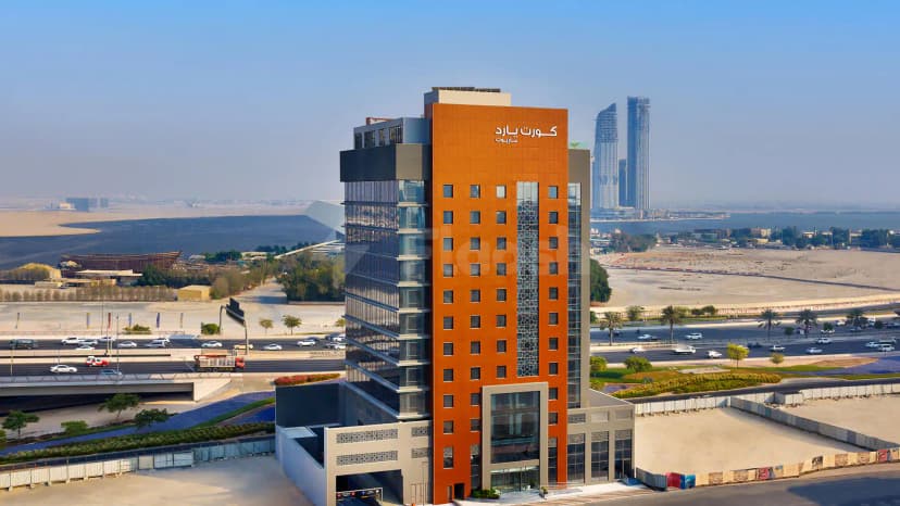 Hotel facade of Courtyard by Marriott Culture Village in Dubai featuring an orange panel with Arabic signage