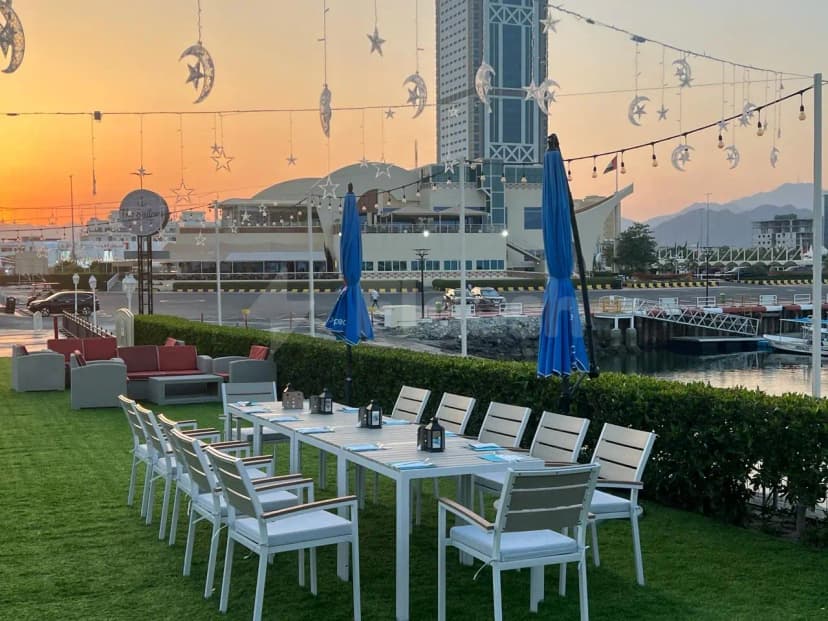Rooftop terrace at The Sailors Fujairah with green artificial grass, hanging star and moon decorations, and a waterfront