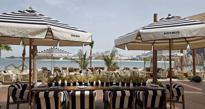 Terrace at Bebabel The Palm Restaurant in Dubai featuring striped umbrellas and a waterfront view with city skyline