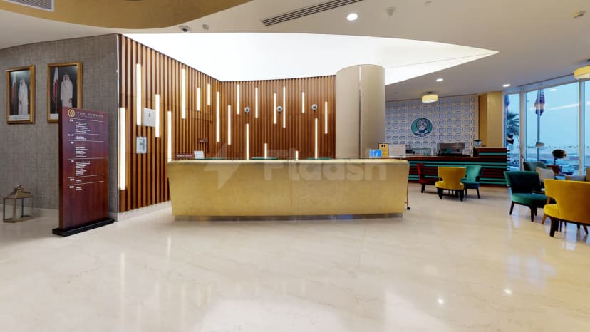 Entrance hall of The Avenue Hotel in Doha featuring a gold reception desk and a wooden slat wall
