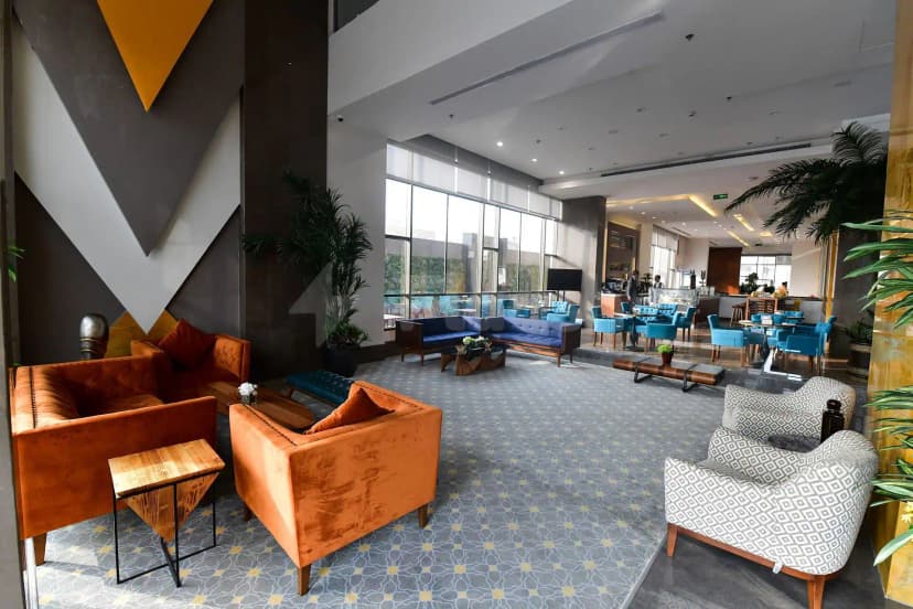 Entrance hall at Warwick Hotel Jeddah featuring geometric wall art, large floor-to-ceiling windows, and a patterned grey