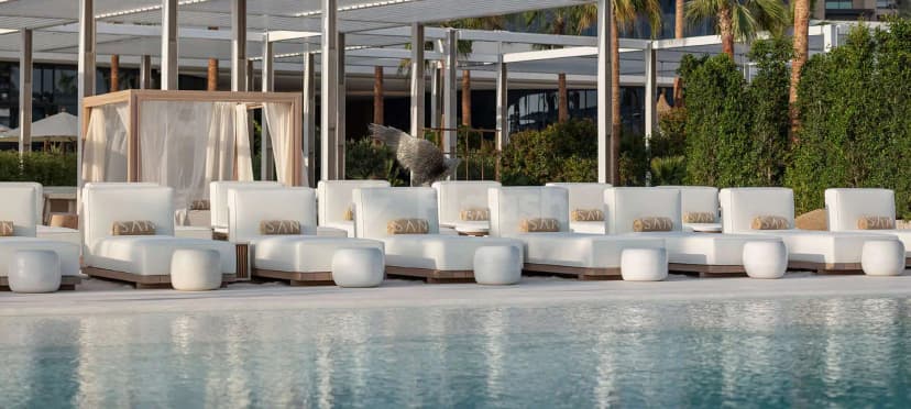 Rooftop terrace at San beach Dubai with white lounge chairs and a decorative sculpture