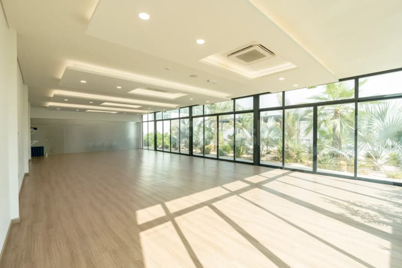 Meeting room at Keyani Wellness in Dubai featuring light wooden flooring and a black-framed glass wall with palm