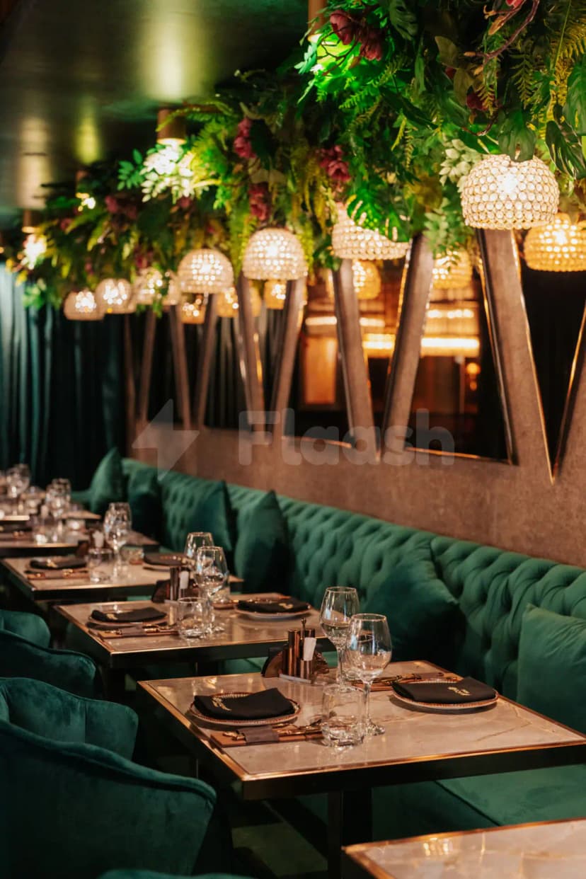 Restaurant interior at Coco Restaurant Al Murooj Dubai featuring green velvet booth seating and hanging crystal pendant lights