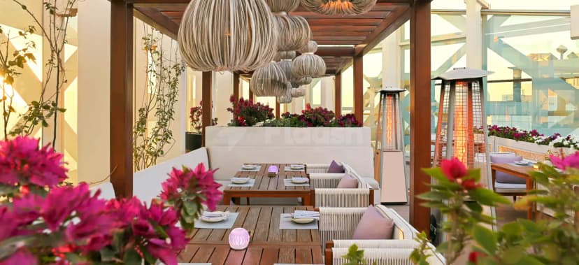 Rooftop terrace at Shaza Doha featuring a wooden pergola and hanging rope light fixtures with white upholstered benches