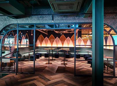 Arched glass partition framing Swingers The Crazy Golf Club Dubai restaurant interior with dark herringbone flooring and pink