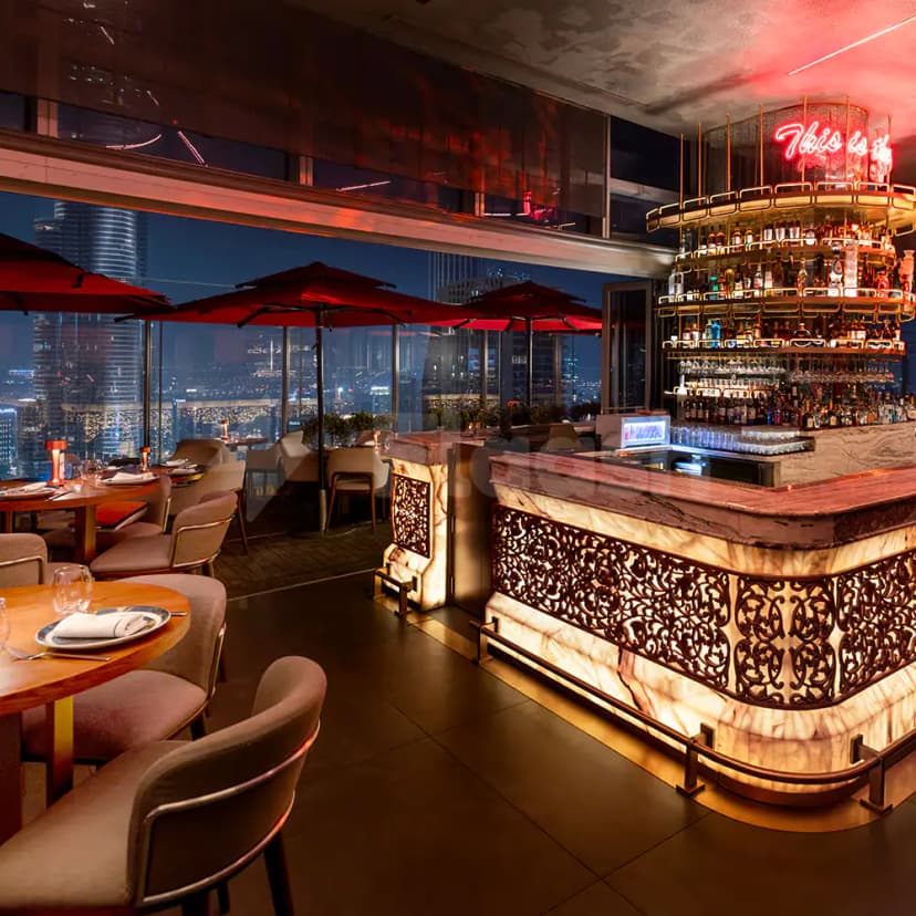 Bar counter at CÉ LA VI Dubai featuring a backlit ornate metal screen and neon sign overlooking
