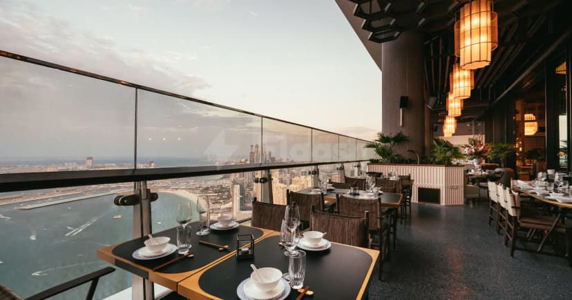 Rooftop terrace at Mott 32 Dubai featuring glass railings and a panoramic city and waterfront view during sunset