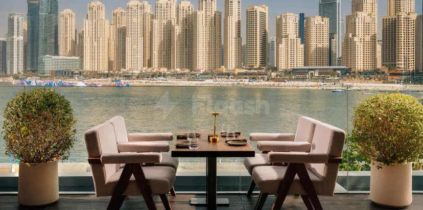 Outdoor dining table at Grand Zor Restaurant Dubai with beige armchairs, glass railing, and a view of
