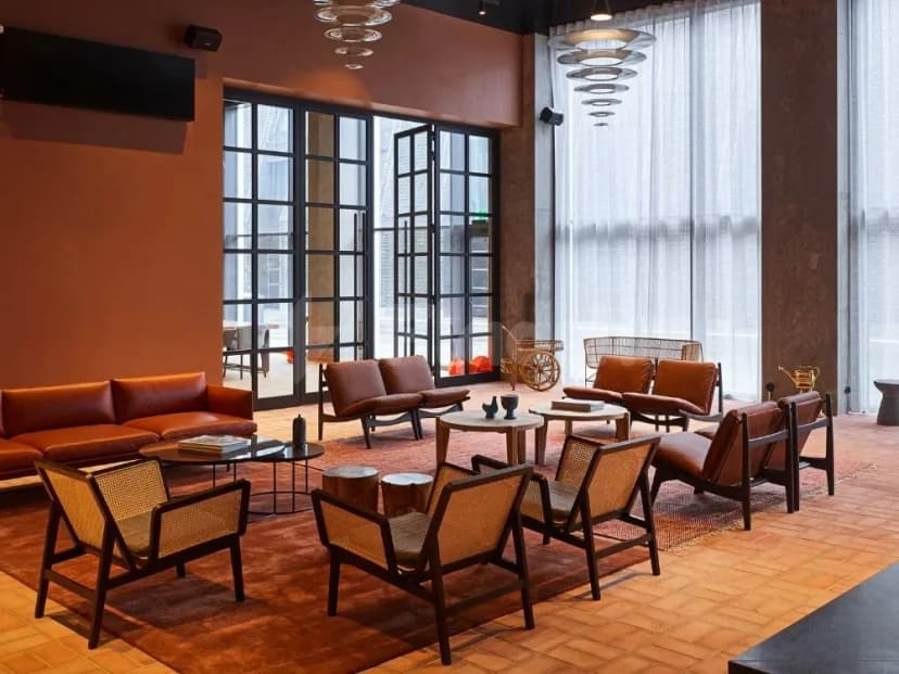 Modern lounge at Ernst Biergarten Restaurant Dubai featuring brown leather sofas, woven cane chairs, large glass doors