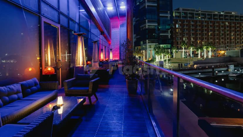 Rooftop terrace at Ornina Arabian Lounge in Abu Dhabi featuring a glass railing, ambient lighting, and a marina