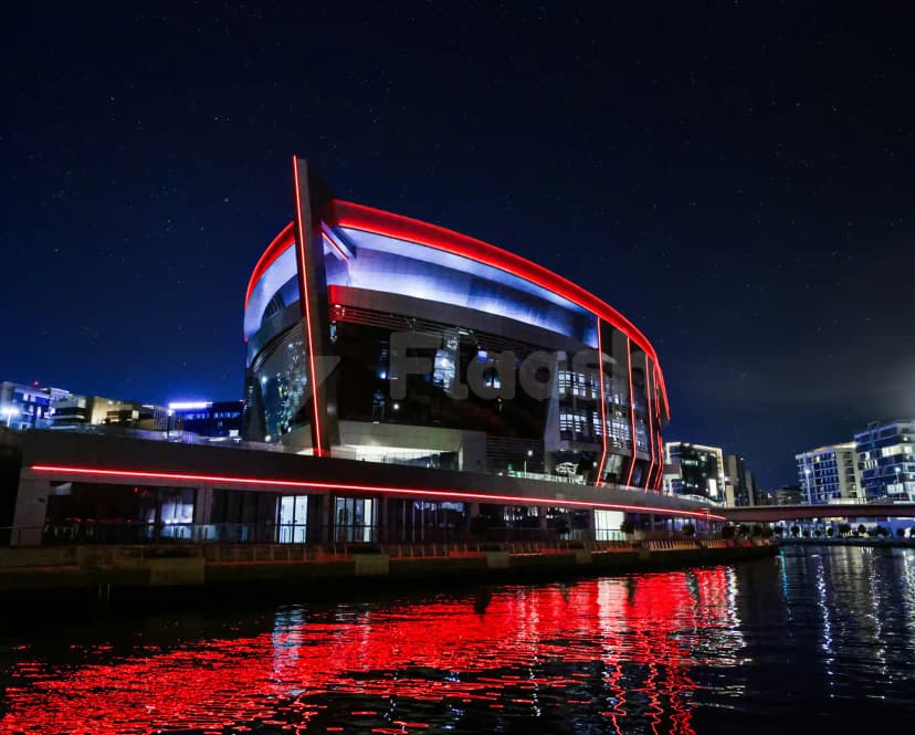 Space42 Arena in Abu Dhabi features a curved glass facade with red LED lighting and a reflective waterfront
