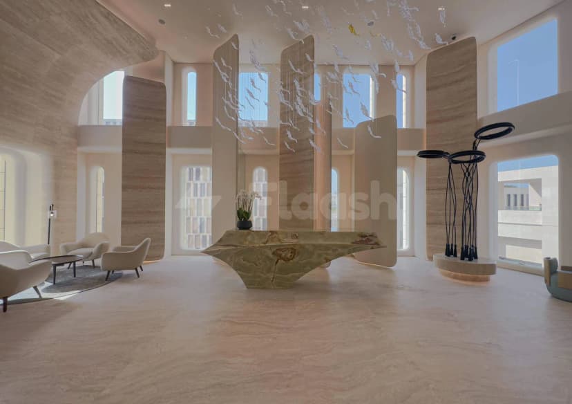 Entrance hall of Sanad Lounge Doha featuring a sculptural green marble reception desk and hanging fish art installation