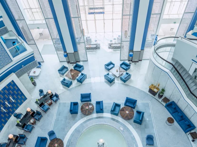Entrance hall at Retaj Salwa Resort & Spa in Doha featuring a high ceiling, blue columns, and a central