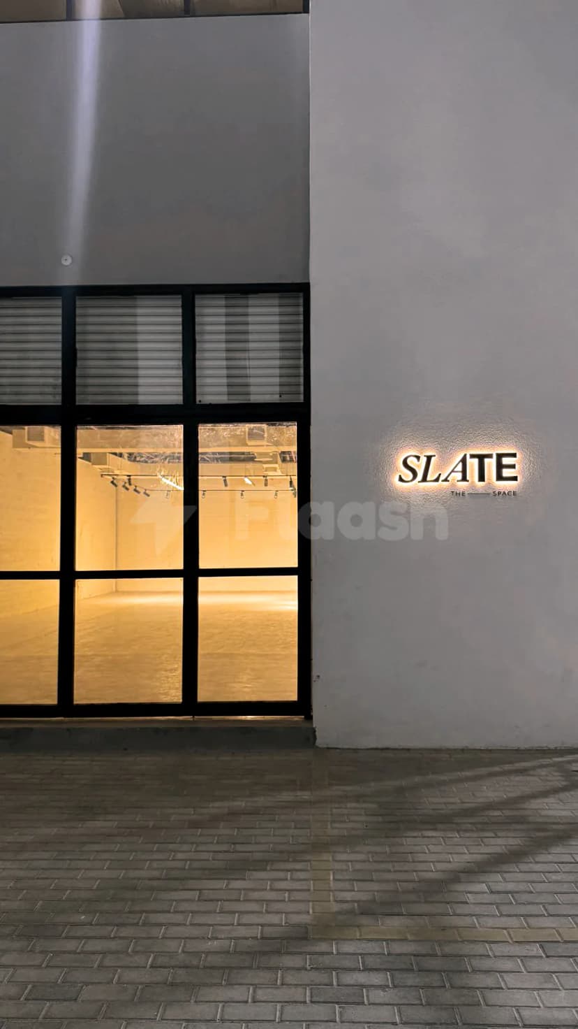 Entrance hall at Slate The Space in Dubai with illuminated signage on white wall