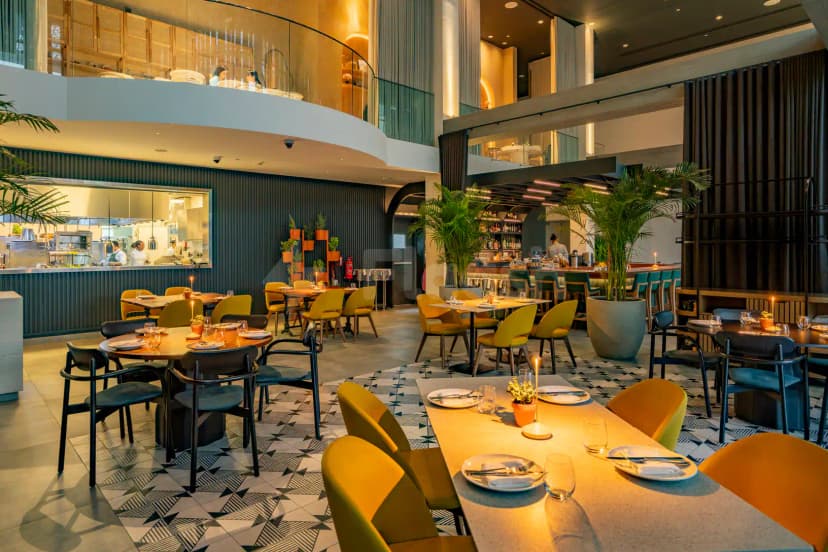 Taparelle Restaurant in Abu Dhabi features a modern multi-level interior with an open kitchen and large potted palms