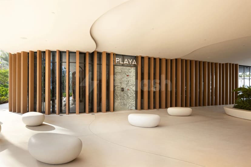 Entrance hall of Playa Dubai featuring a curved ceiling, wooden slat wall, and an engraved glass door