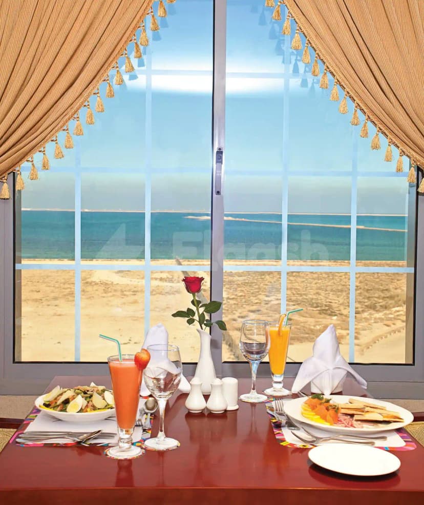 Restaurant at Coral Jubail in Al Jubail featuring a dining table with beach view through large windows