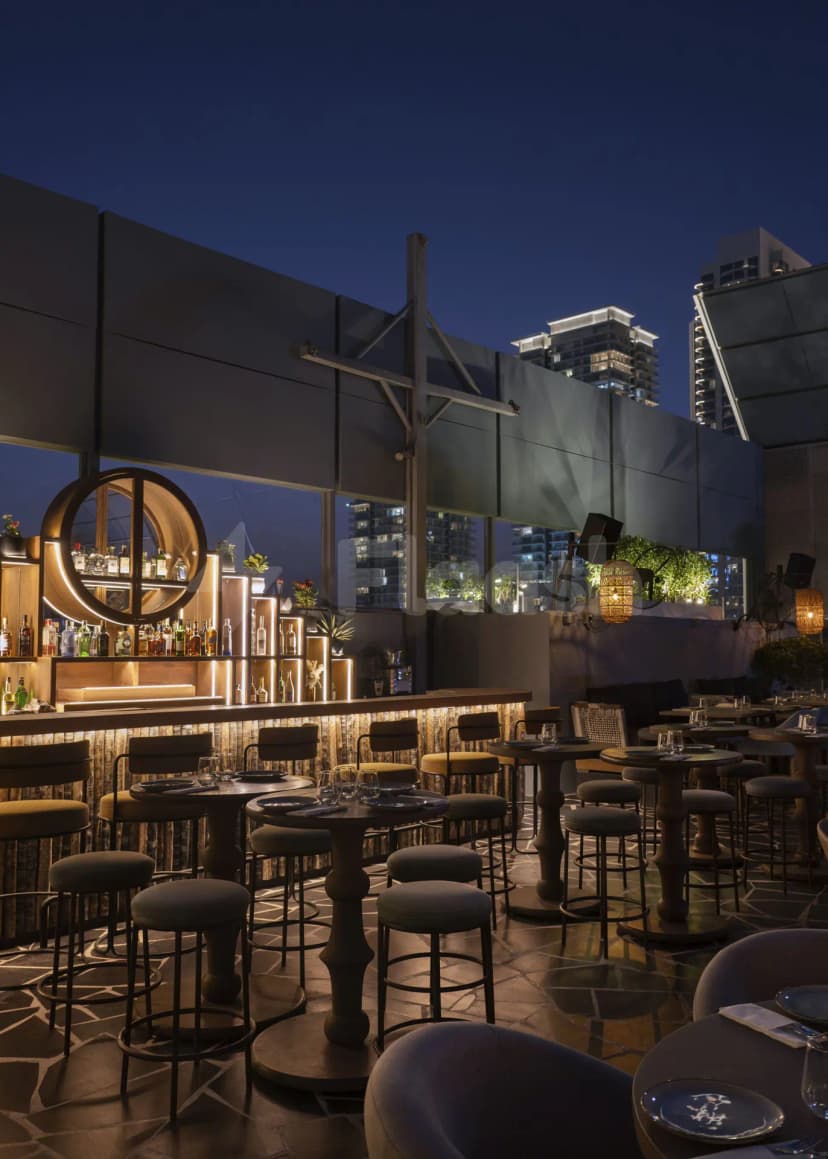 Rooftop terrace at Bar Du Port Dubai featuring an illuminated circular bar shelf and city skyline view
