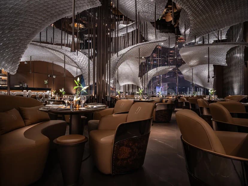Sculptural ceiling installation dominates Doors Dubai Mall Restaurant in Dubai, featuring curved brown seating and round dining tables
