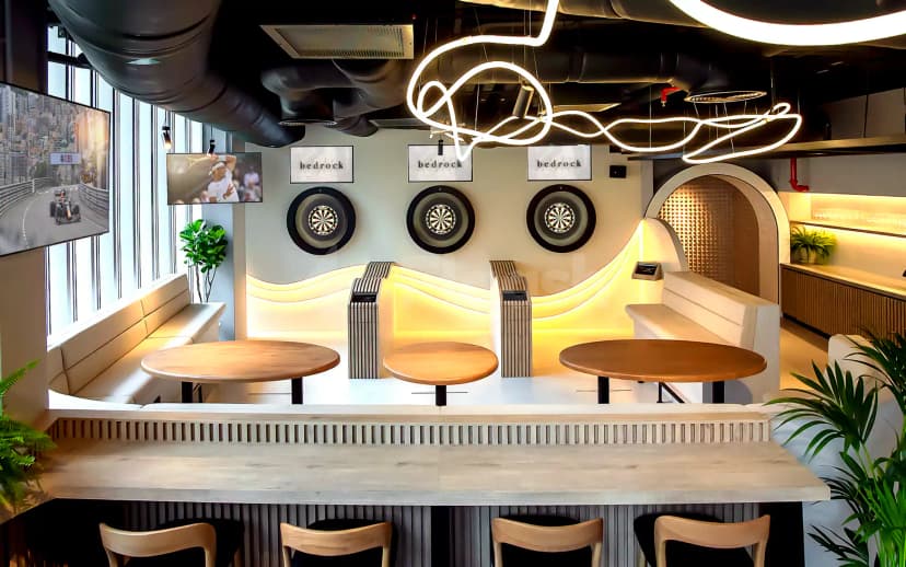 Restaurant at Bedrock Pier 7 in Dubai featuring dartboards on a backlit wave-shaped wall and round wooden tables
