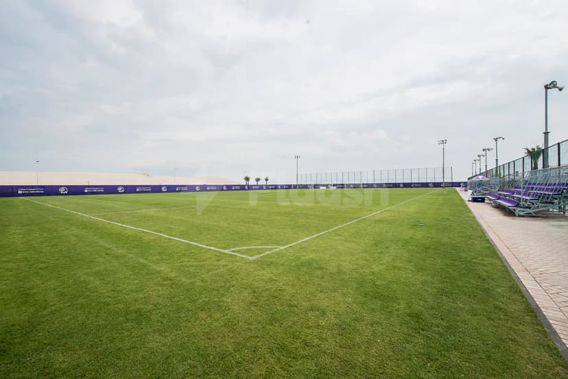 Green artificial turf field at NYU Abu Dhabi Athletic Field in Abu Dhabi with purple spectator seating