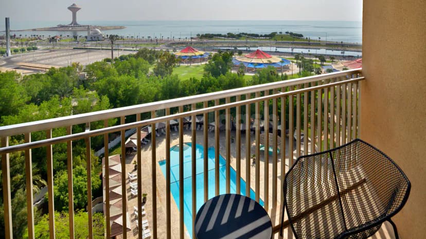 Rooftop terrace at Le Meridien Al Khobar overlooking a swimming pool, green park, and sea with a modern