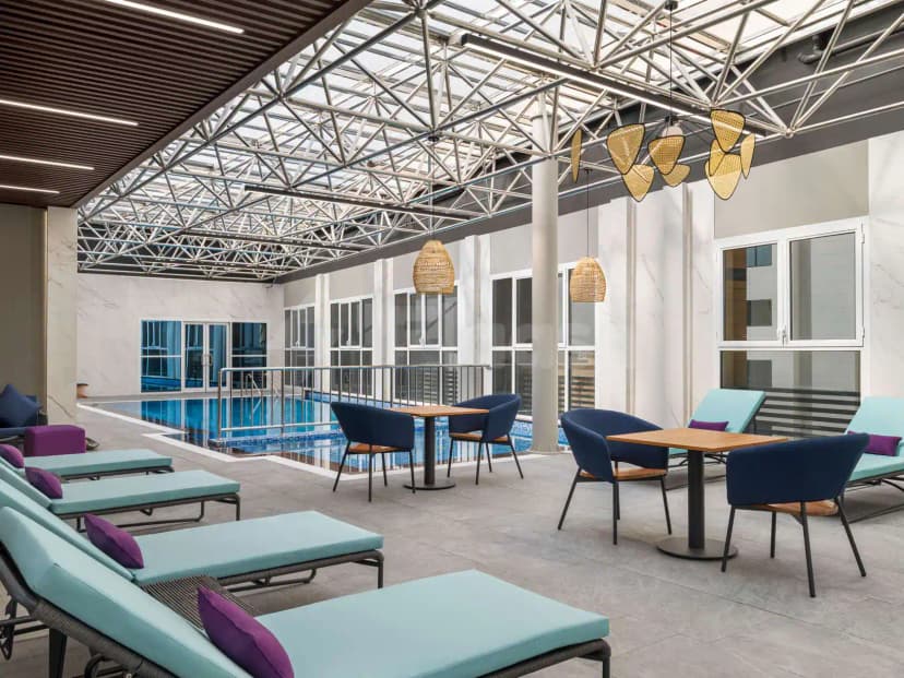 Indoor swimming pool at Mercure Riyadh Al Anoud featuring a glass roof with metal truss structure and white