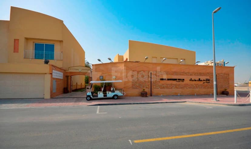Hotel facade of Coral Boutique Villas in Dubai featuring an orange stone wall, arched entrance, and a parked