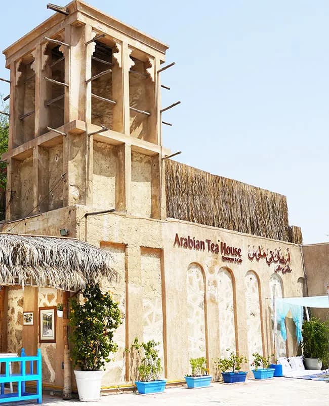 Hotel facade of Arabian Tea House Restaurant & Cafe in Sharjah featuring a traditional wind tower and thatched roof