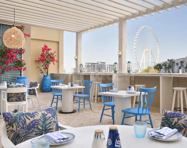 Rooftop terrace at JA Ocean View Hotel Dubai featuring a white pergola ceiling and a distant ferris wheel