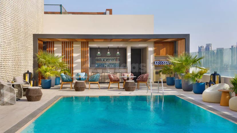 Rooftop terrace at Courtyard by Marriott Culture Village, Dubai, featuring a rectangular pool and an outdoor bar