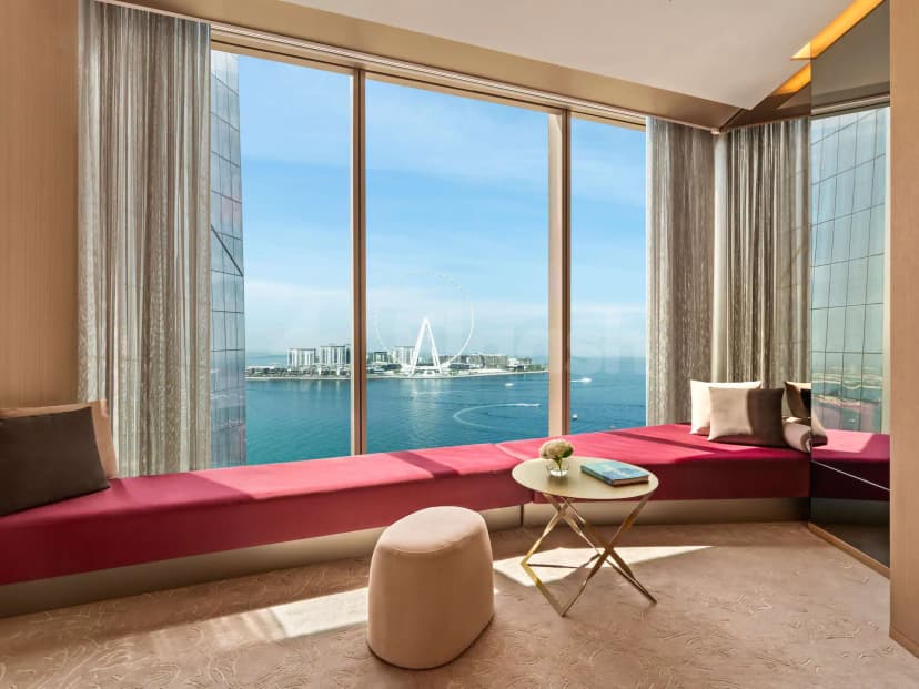 Terrace at Rixos Premium Dubai JBR Hotel featuring a red upholstered bench and floor-to-ceiling windows overlooking Dubai’s