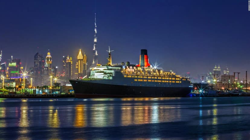 Theatre by QE2 rooftop terrace at night with the illuminated QE2 cruise ship docked nearby and Burj Khalifa