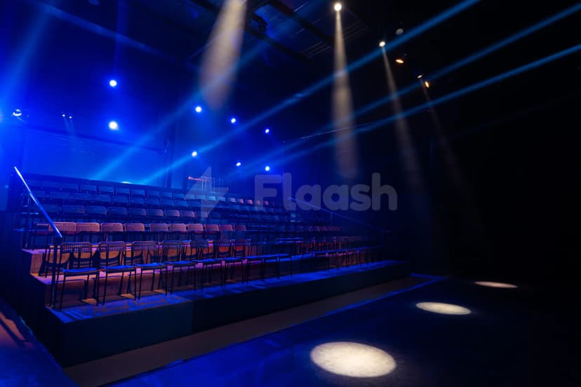 Tiered seating area at Sima Performing Arts Dubai with black chairs, blue theatrical lighting, and spotlights