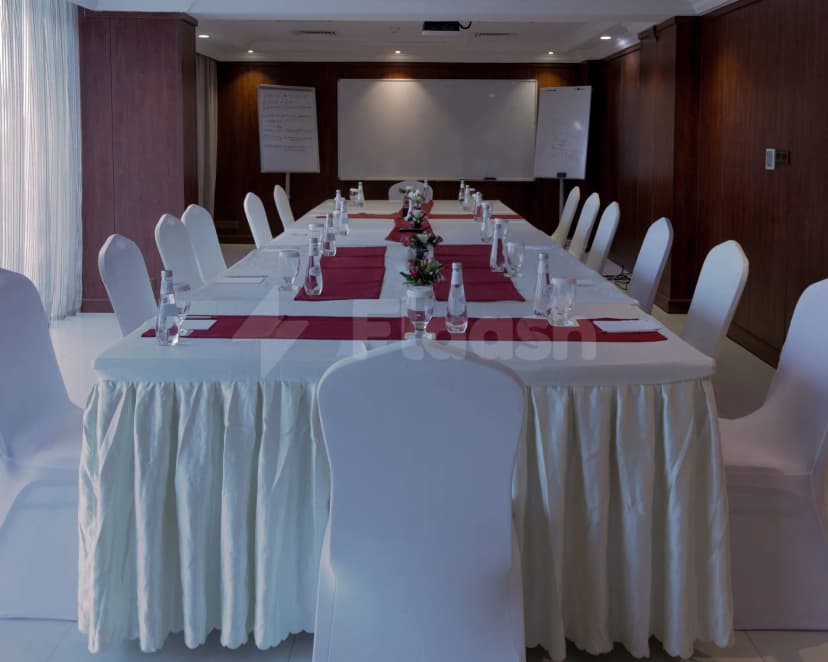 Boardroom at Crown Tower Al Jubail in Al Jubail with long table, white chairs, red runners, and whiteboards