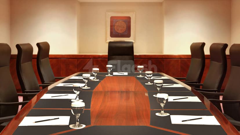 Boardroom at Le Meridien Towers in Makkah featuring a long polished wooden table with black placemats and framed