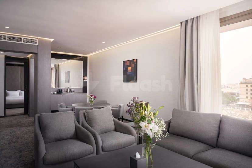 Meeting room at Joudyan King Road Jeddah by Elaf featuring a grey sofa, armchairs, and a large window