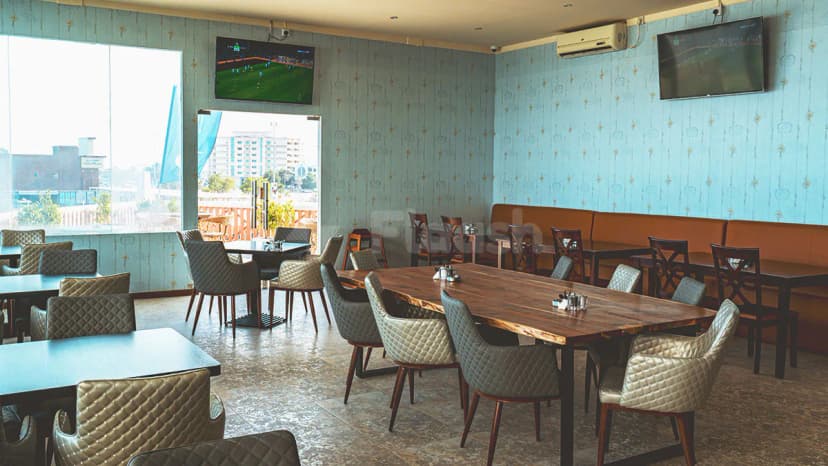 Restaurant at The Sailors Fujairah in Fujairah with wooden tables and light blue patterned wallpaper