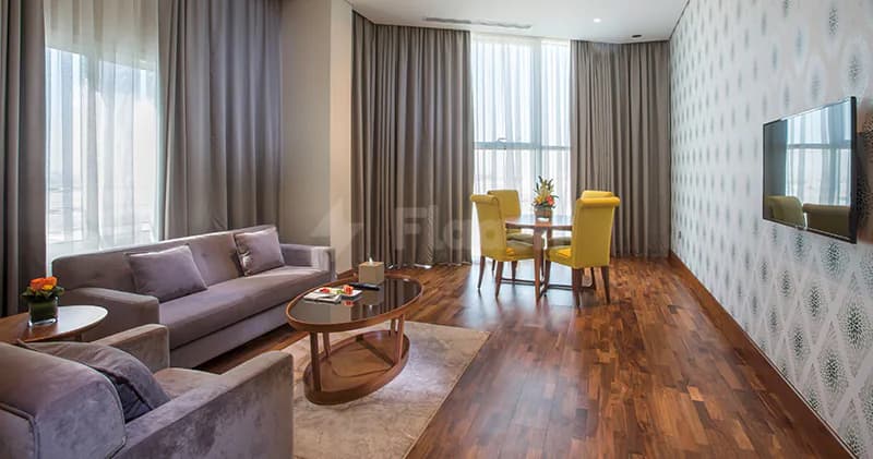 Meeting room at The Avenue Hotel in Doha featuring a grey velvet sofa, yellow dining chairs, and patterned