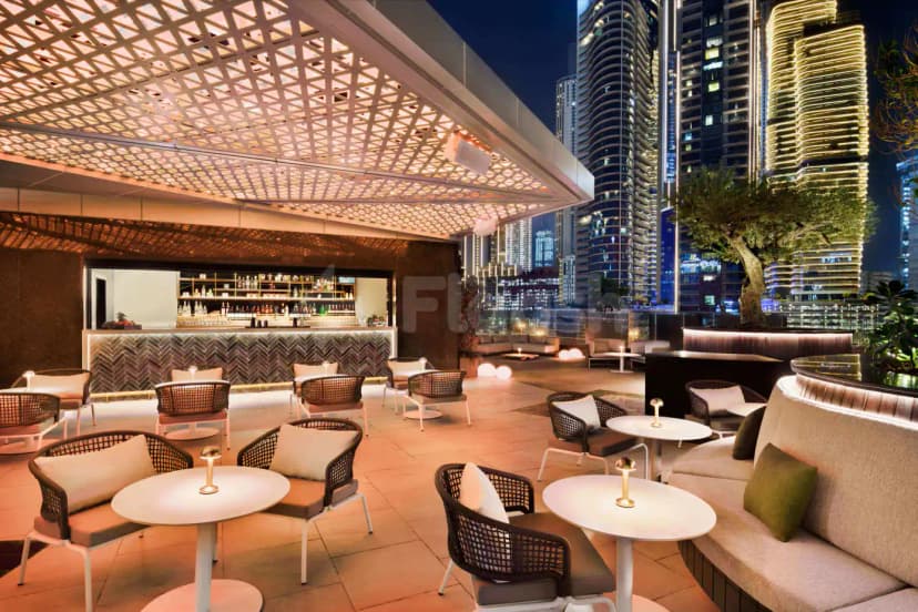 Rooftop terrace at Open Sesame Dubai featuring a geometric lattice ceiling and illuminated skyscrapers in the background