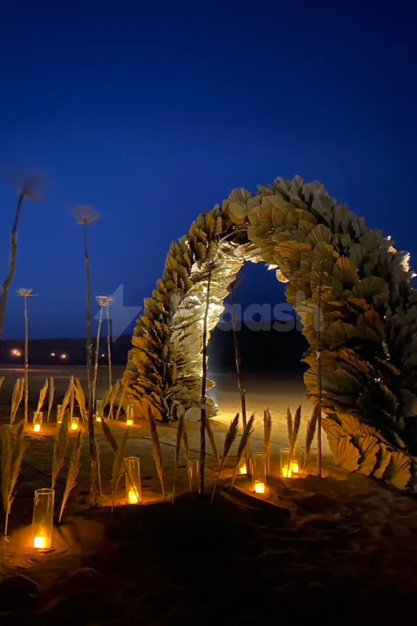 Beach at Nara Desert Escape in Dubai with a large leaf arch illuminated by candles
